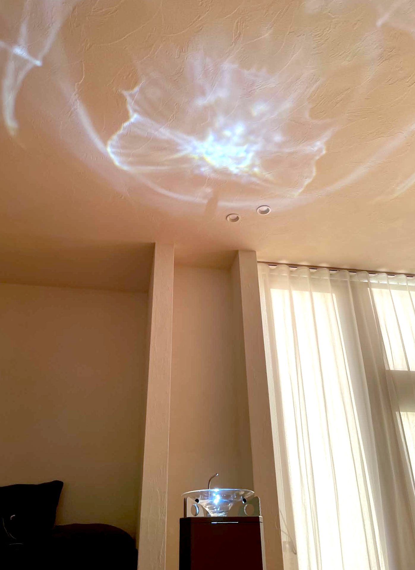 Brainwave Rippleの設置写真。水を使った装置から広がる光の模様が室内の天井に映っている